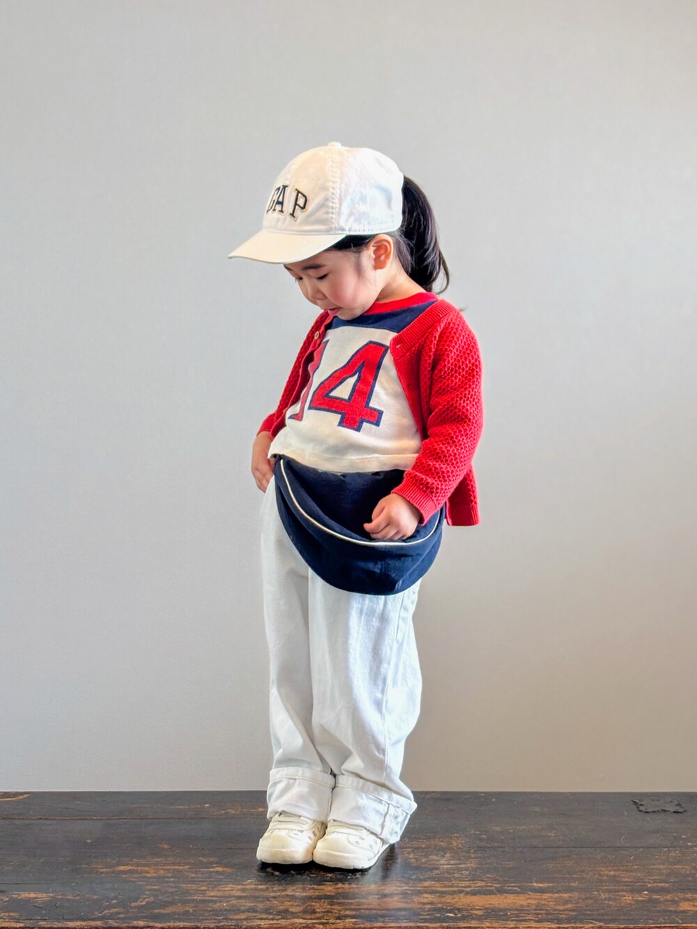 ベージュ系のスニーカー、レッド系のTシャツ/カットソー、レッド系のカーディガン/ボレロを着用したキッズの春コーディネートの2枚目の写真