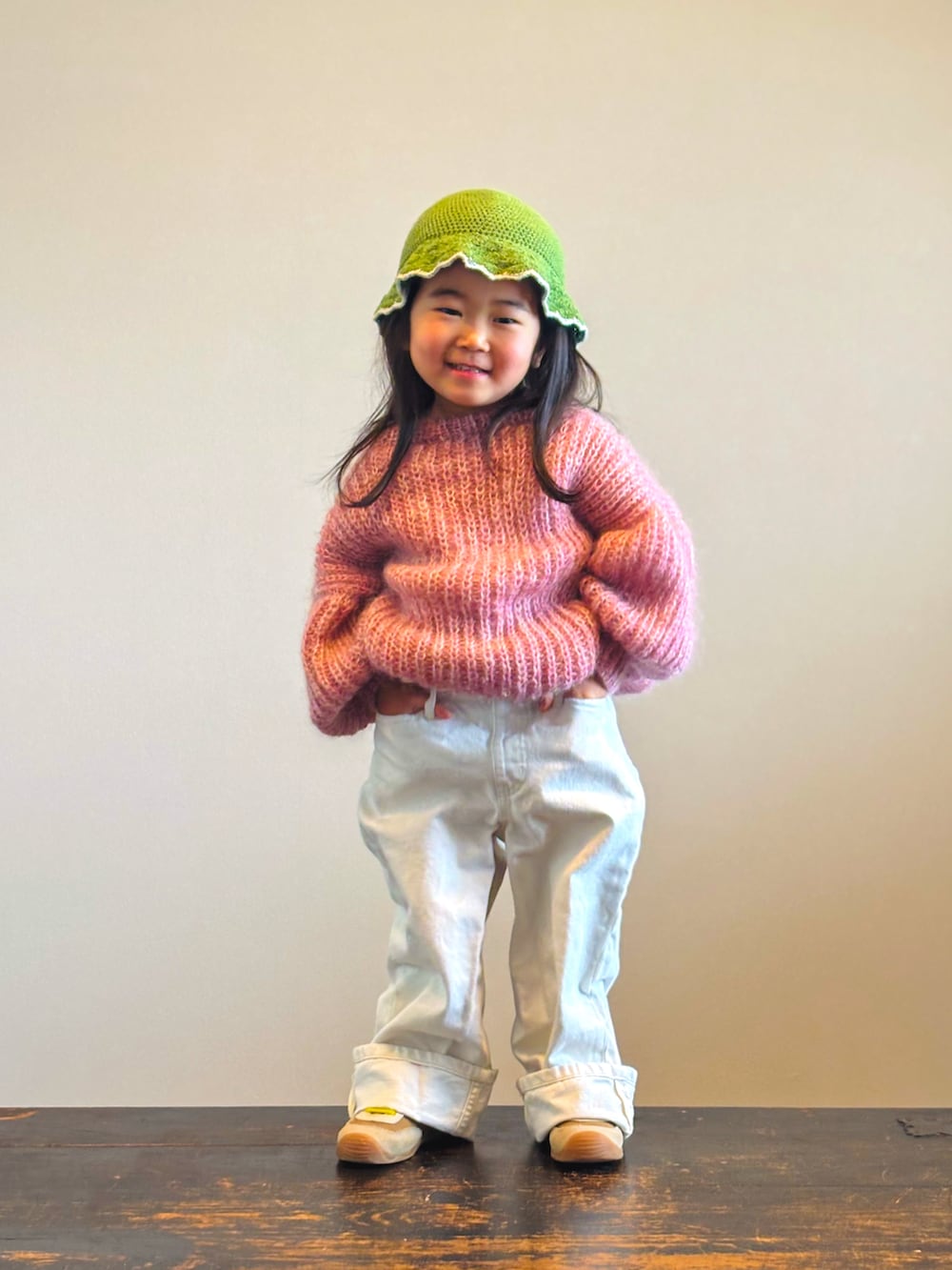 イエロー系のスニーカー、ピンク系のニット/セーター、ホワイト系のデニムパンツを着用したキッズの冬コーディネートの2枚目の写真