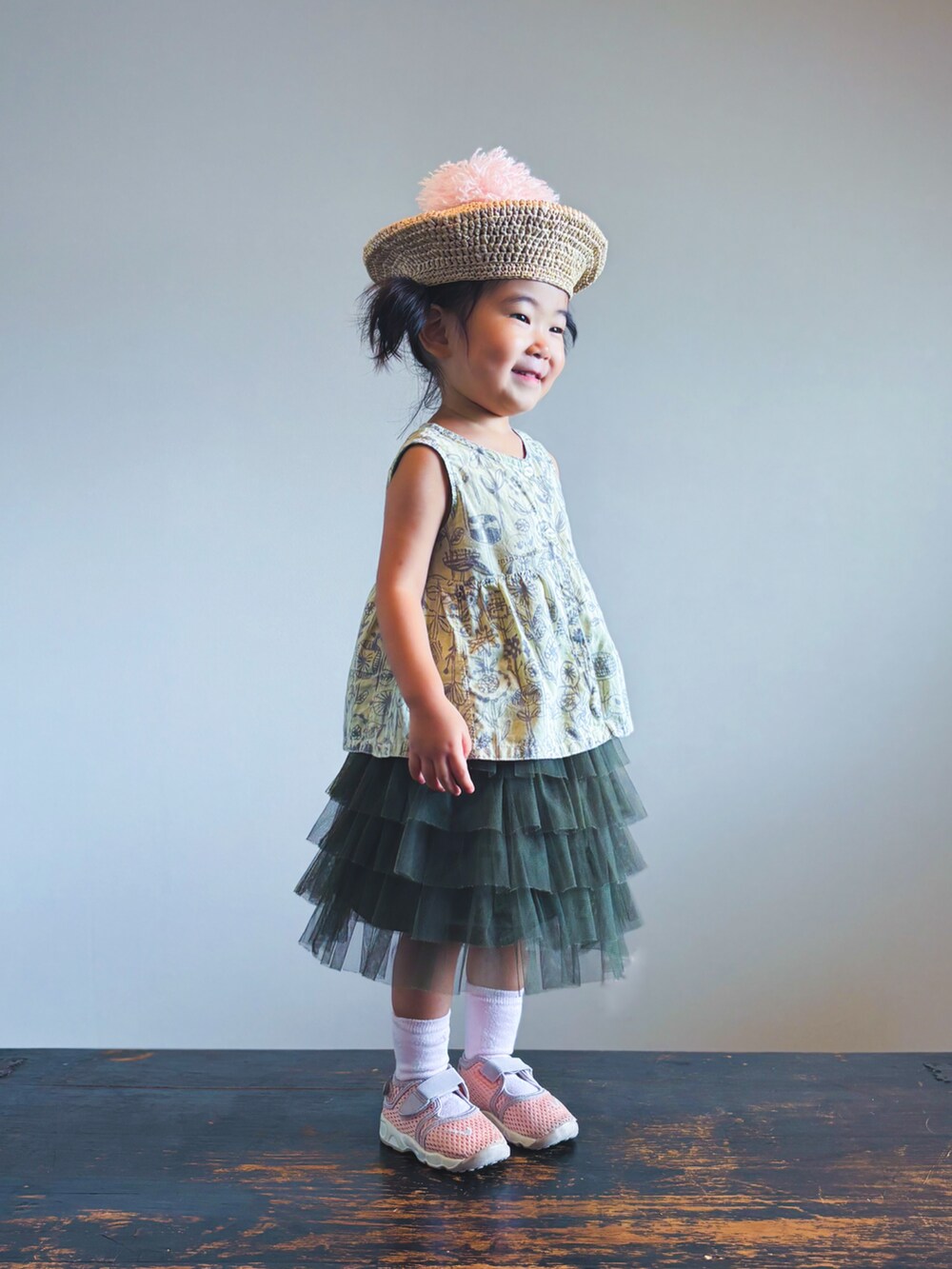 グリーン系のスカート、ピンク系のスニーカー、ベージュ系のワンピースを着用したキッズの夏コーディネートの3枚目の写真