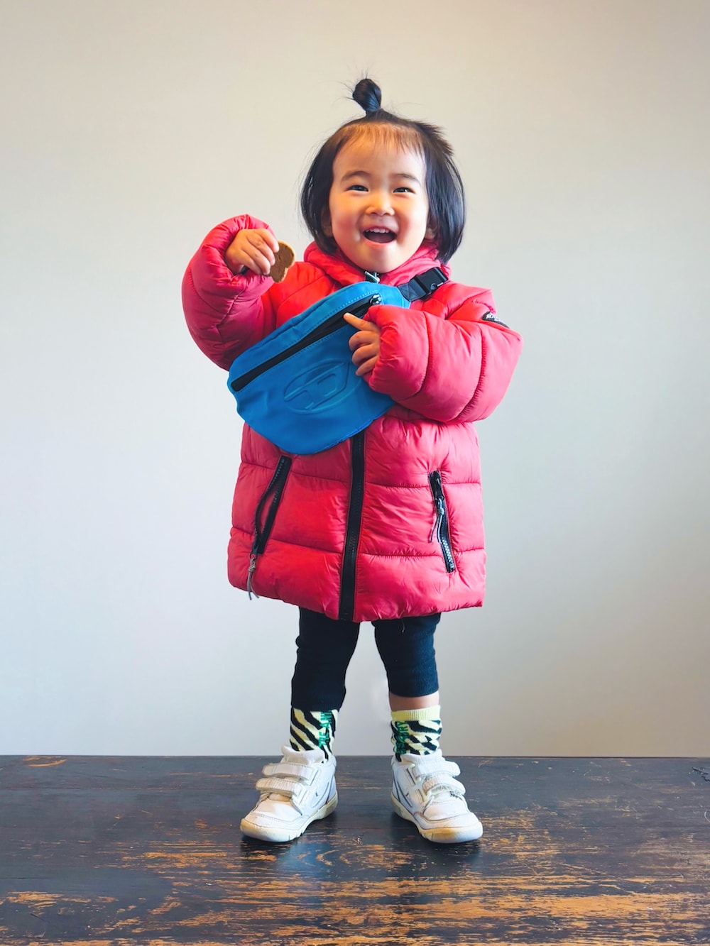 レッド系のダウンジャケット/コート、ブルー系のボディバッグ/ウエストポーチ、ブラック系のその他パンツを着用したキッズの冬コーディネートの3枚目の写真