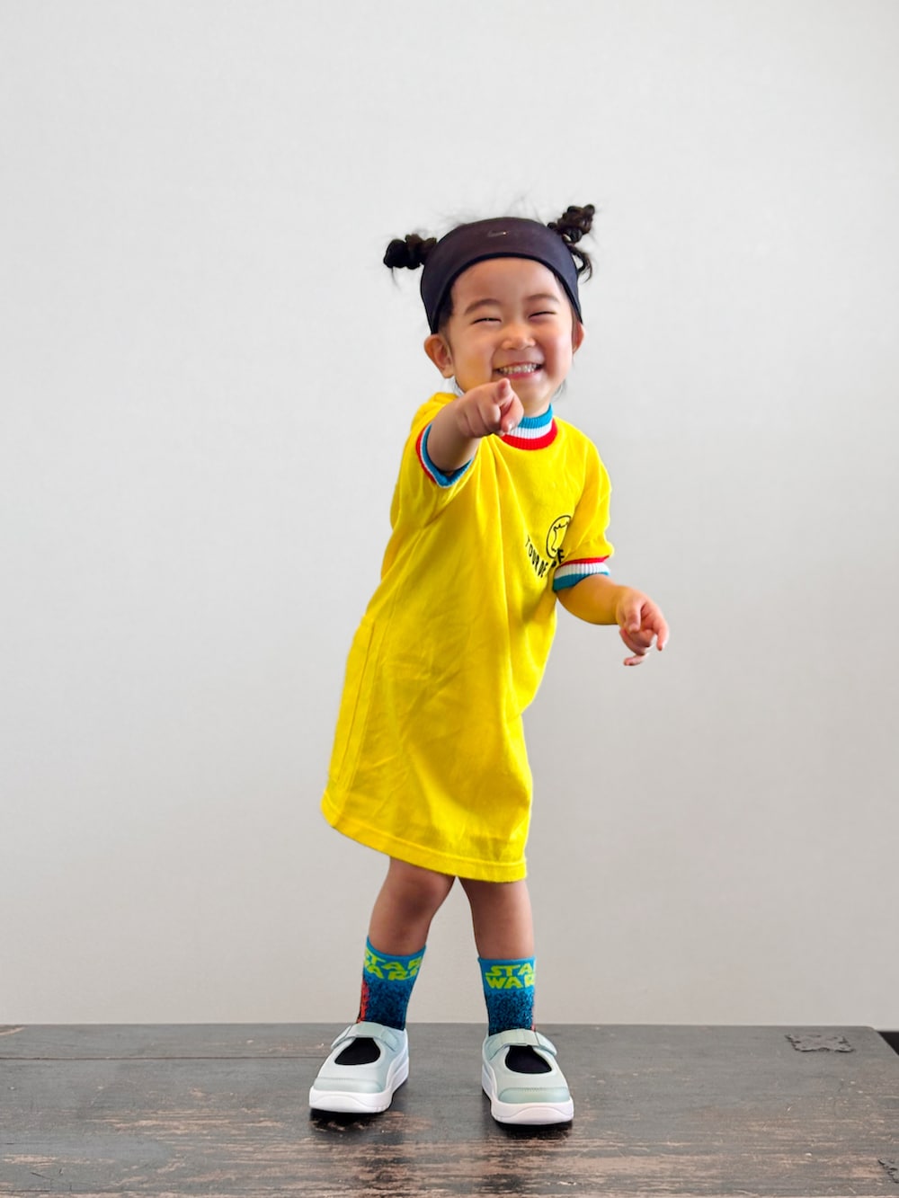 グリーン系のスニーカー、イエロー系のTシャツ/カットソー、ブラック系のヘアバンドを着用したキッズの夏コーディネートの3枚目の写真