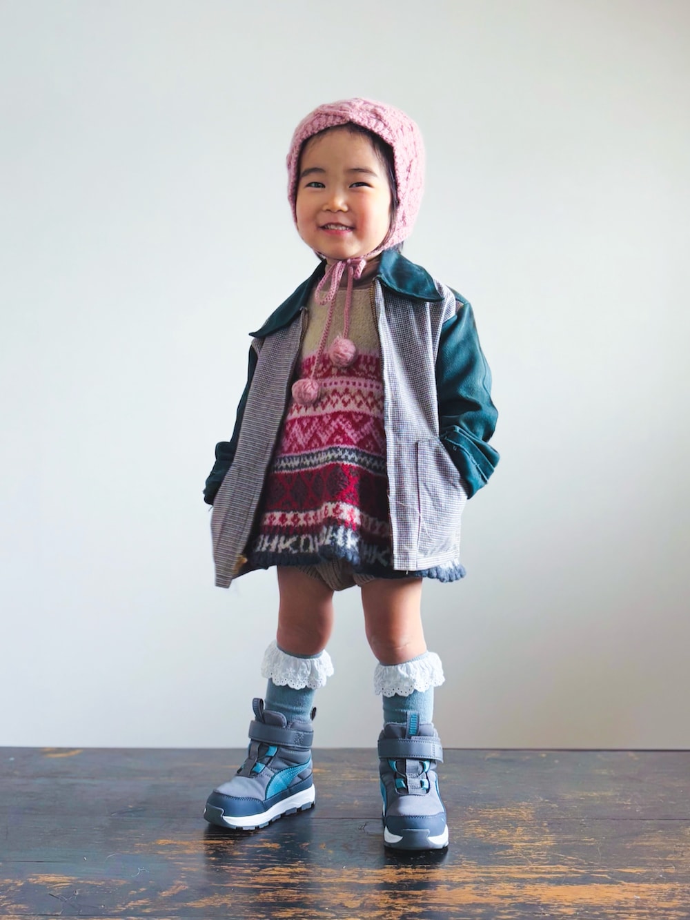 レッド系のワンピース、ブラウン系のセットアップ、グリーン系のその他アウターを着用したキッズの冬コーディネートの3枚目の写真