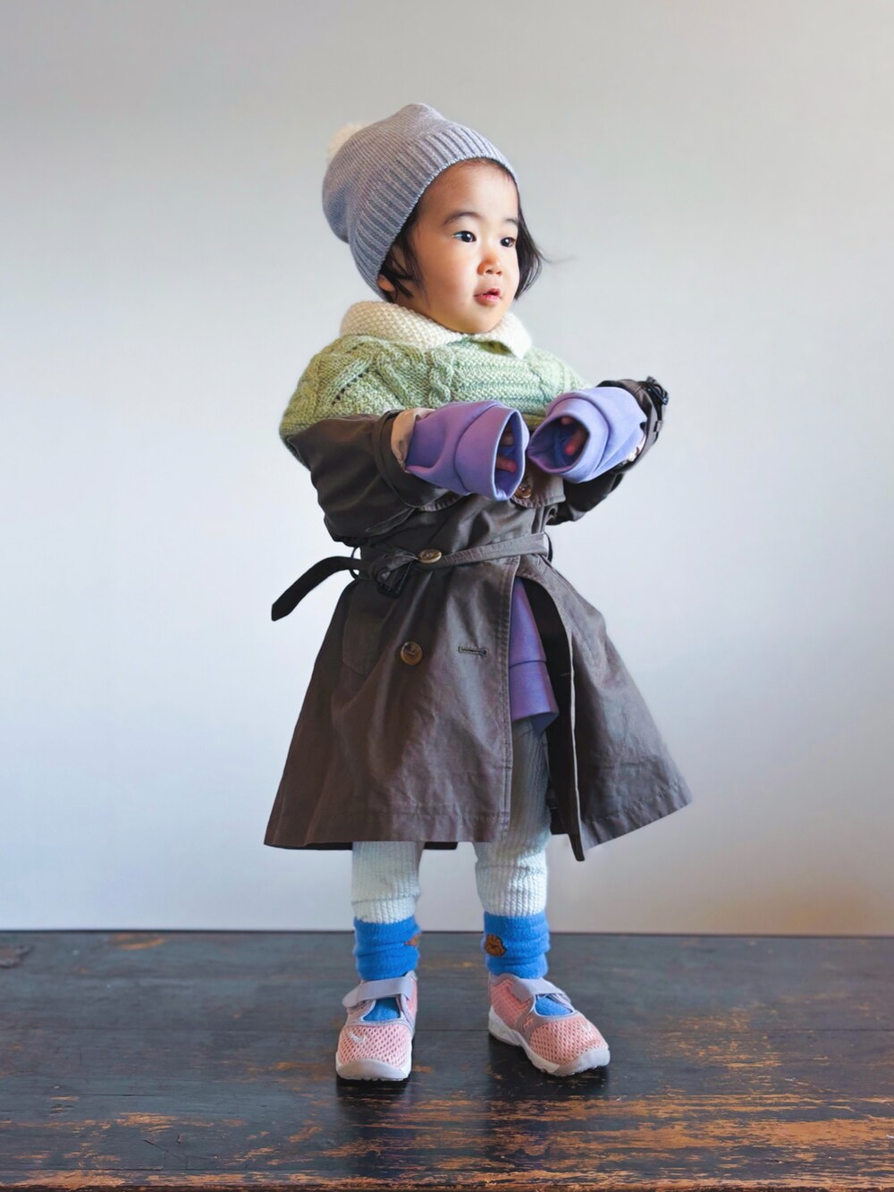 グリーン系のポンチョ、グリーン系のトレンチコート、パープル系のスウェットを着用したキッズの冬コーディネートの3枚目の写真