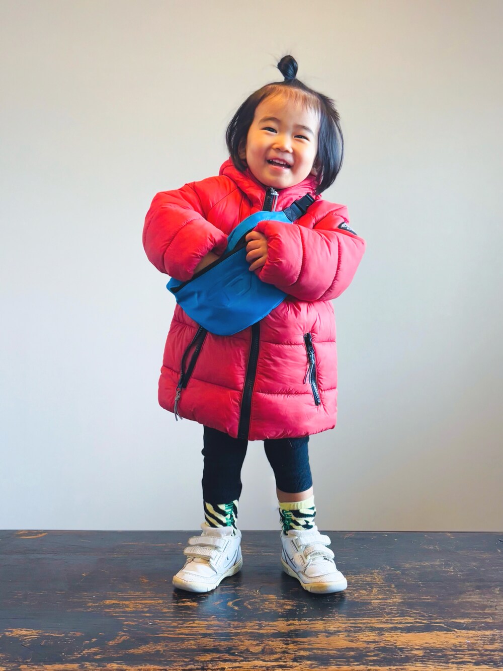 レッド系のダウンジャケット/コート、ブルー系のボディバッグ/ウエストポーチ、ブラック系のその他パンツを着用したキッズの冬コーディネートの2枚目の写真