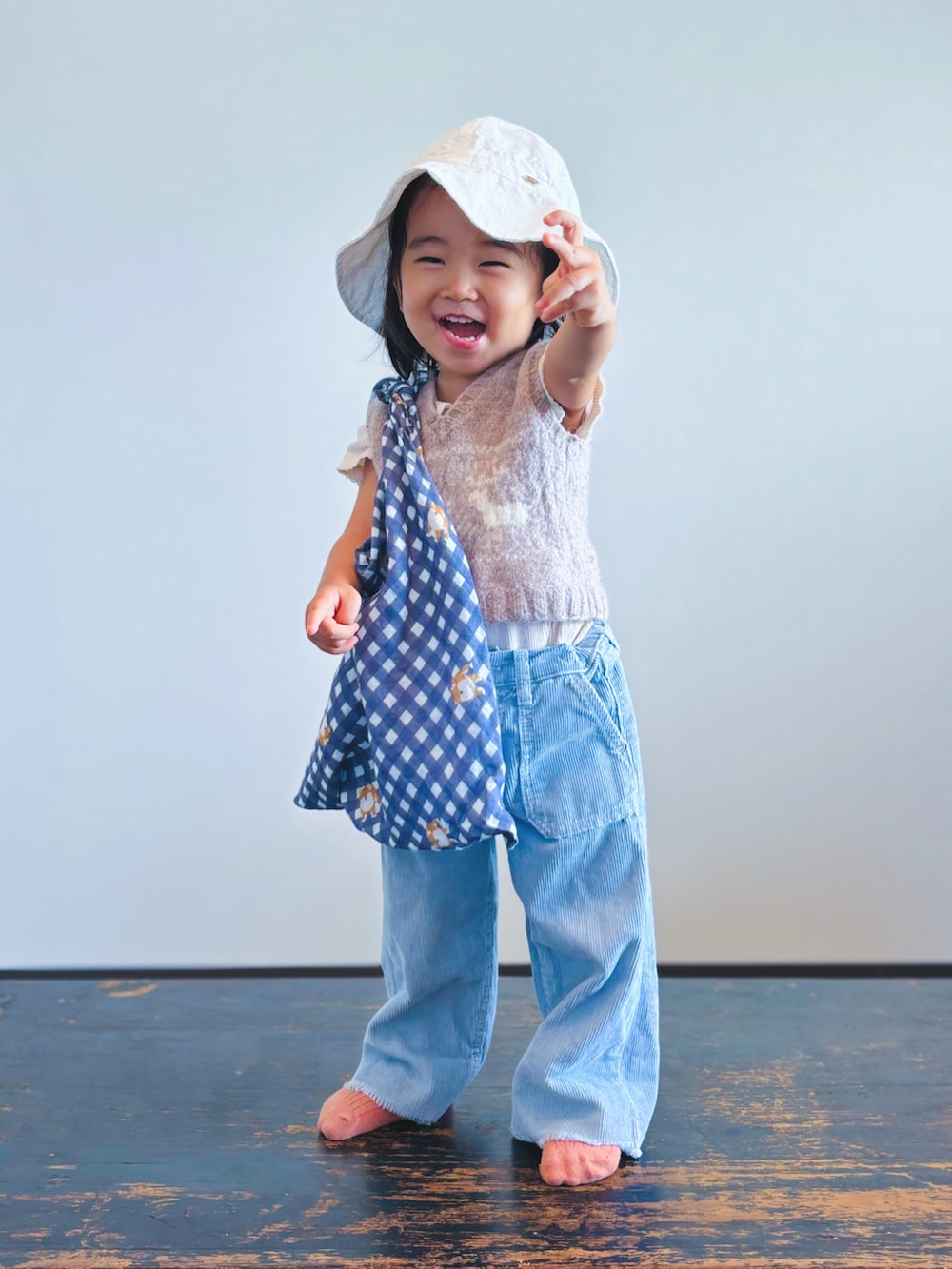 ベージュ系のベスト、ブルー系のパンツ、ホワイト系のハットを着用したキッズの秋コーディネートの2枚目の写真