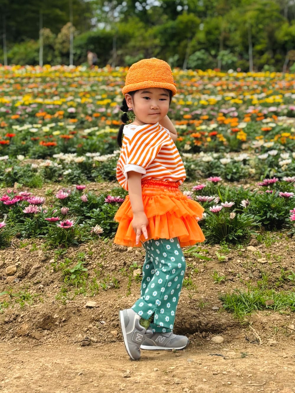 グリーン系のその他パンツ、オレンジ系のスカート、グレー系のスニーカーを着用したキッズの春コーディネートの2枚目の写真