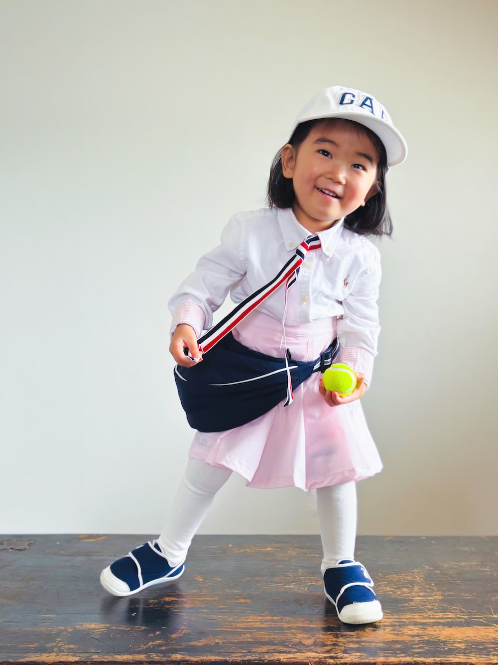 ブルー系のスニーカー、ピンク系のスカート、ブルー系のショルダーバッグを着用したキッズの春コーディネートの2枚目の写真