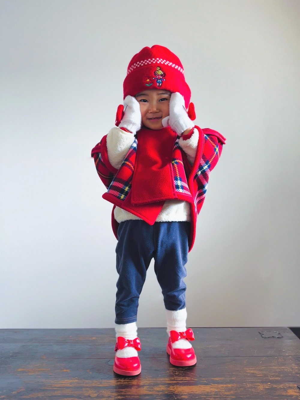 ブルー系のデニムパンツ、レッド系のドレスシューズ、レッド系のポンチョを着用したキッズの冬コーディネートの3枚目の写真
