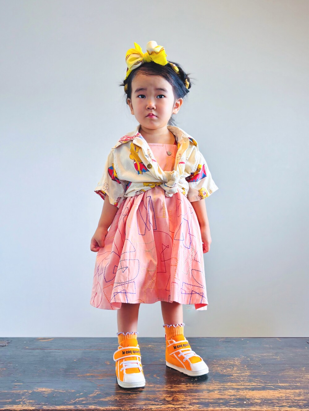 オレンジ系のスニーカー、オレンジ系のワンピース、ベージュ系のシャツ/ブラウスを着用したキッズの夏コーディネートの3枚目の写真