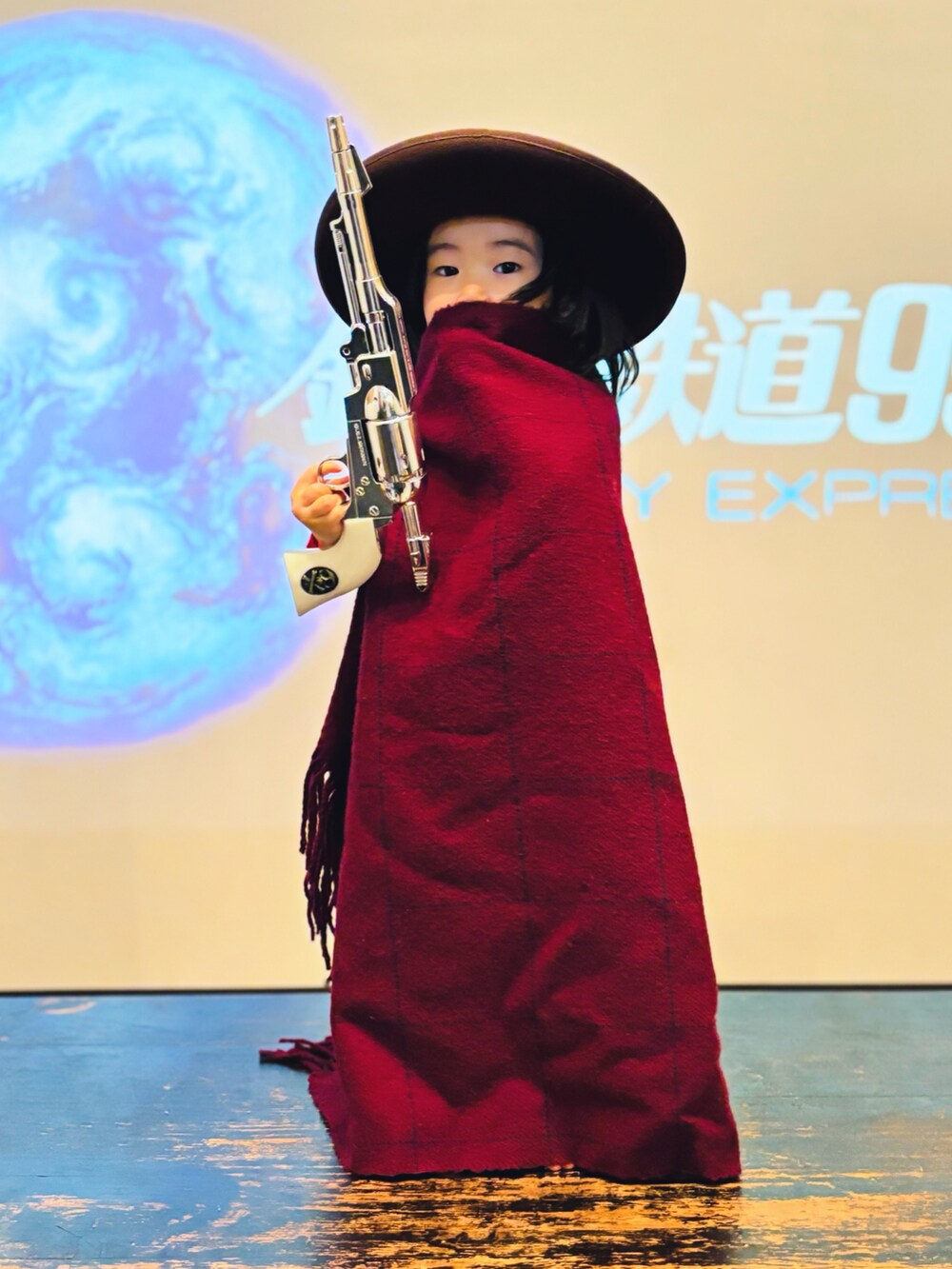 ブラウン系のハット、レッド系のブランケット、シルバー系のおもちゃを着用したキッズの秋コーディネートの2枚目の写真