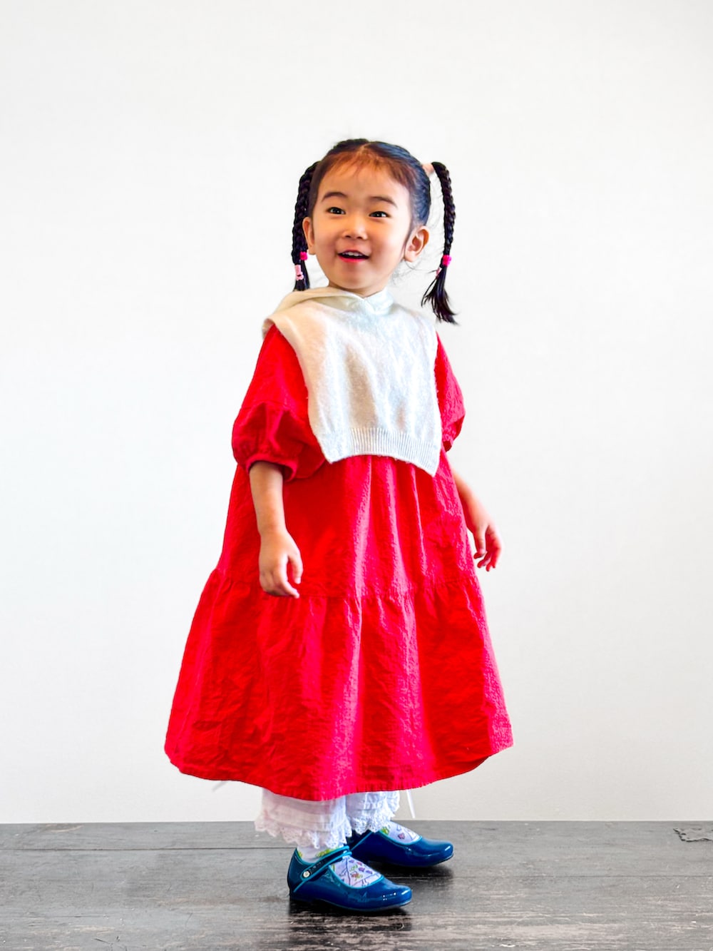レッド系のワンピース、ホワイト系のその他パンツ、ブルー系のドレスシューズを着用したキッズの秋コーディネートの2枚目の写真
