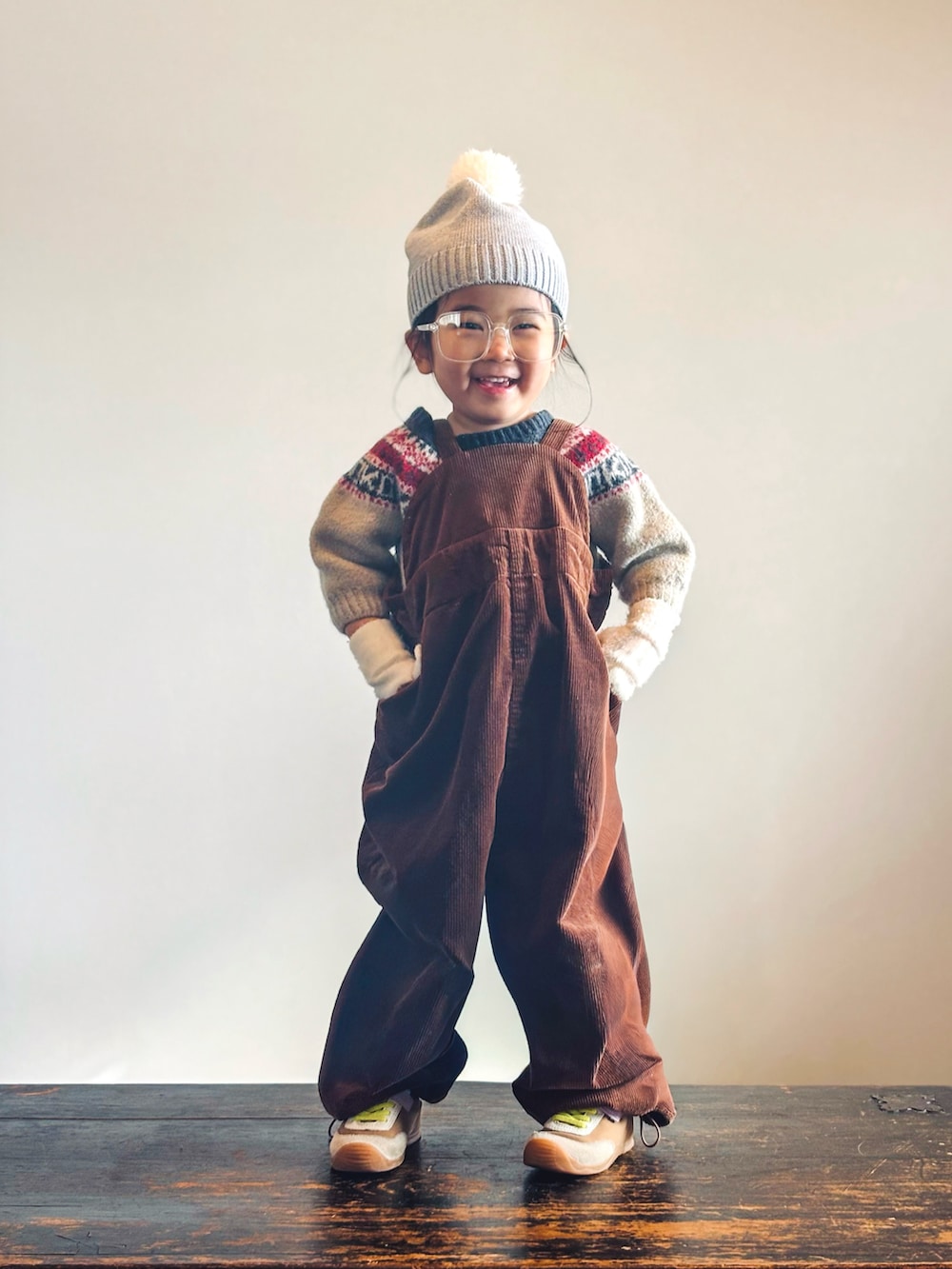 イエロー系のスニーカー、ベージュ系のニット/セーター、ブラウン系のサロペット/オーバーオールを着用したキッズの冬コーディネートの3枚目の写真