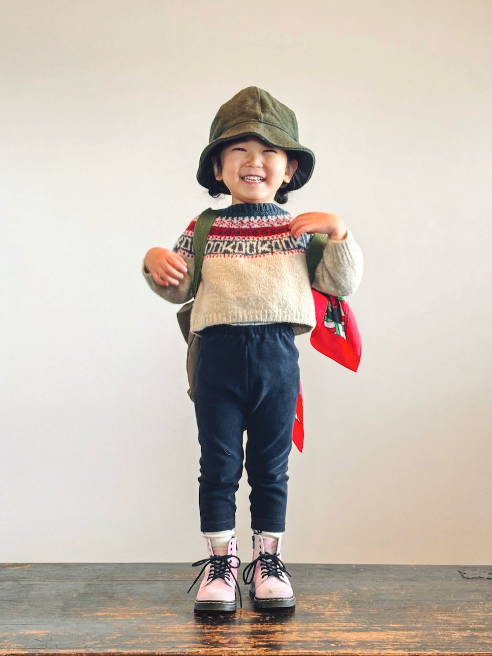ベージュ系のニット/セーター、ブラック系のパンツ、グリーン系のバックパック/リュックを着用したキッズの秋コーディネートの3枚目の写真
