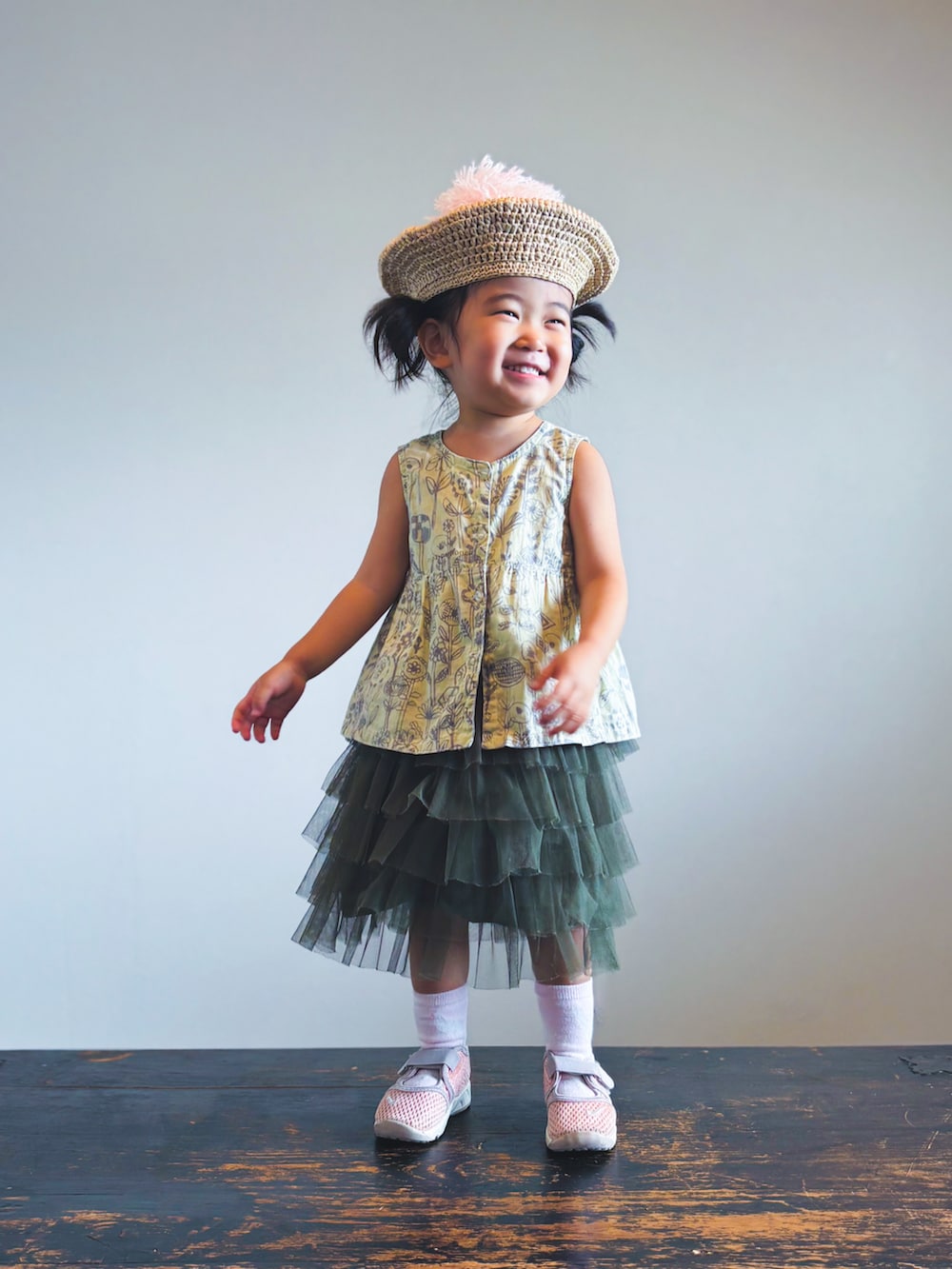 グリーン系のスカート、ピンク系のスニーカー、ベージュ系のワンピースを着用したキッズの夏コーディネートの2枚目の写真