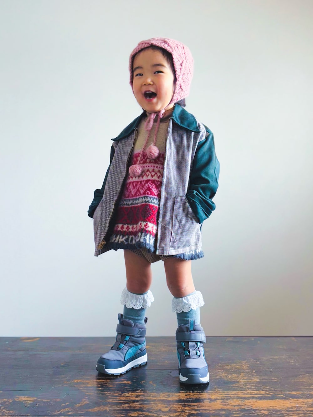 レッド系のワンピース、ブラウン系のセットアップ、グリーン系のその他アウターを着用したキッズの冬コーディネートの2枚目の写真