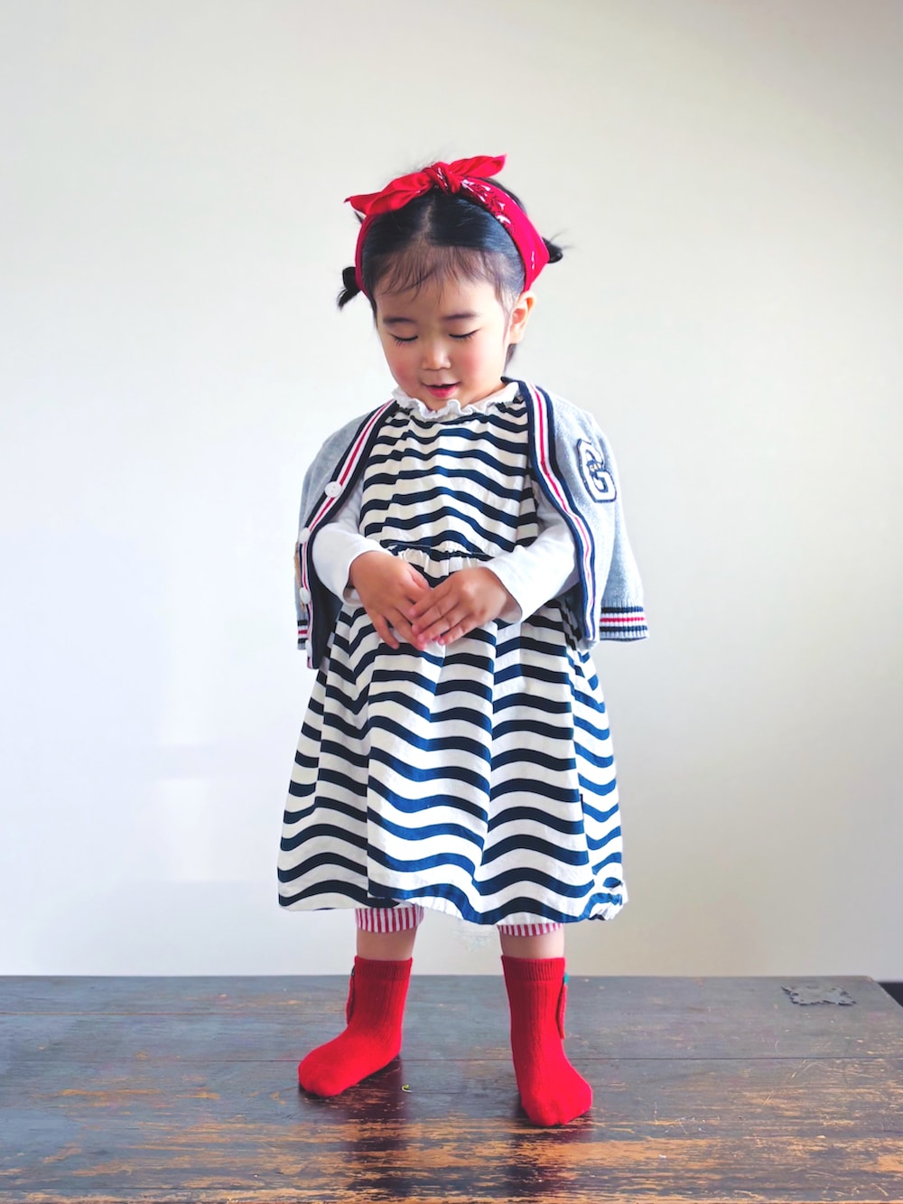 ブラック系のワンピース、ホワイト系のTシャツ/カットソー、グレー系のカーディガン/ボレロを着用したキッズの春コーディネートの2枚目の写真