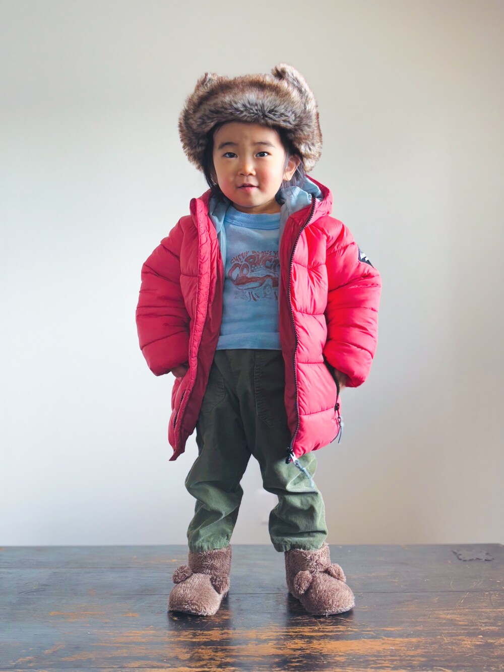 グリーン系のパンツ、ブラウン系のその他シューズ、レッド系のダウンジャケット/コートを着用したキッズの冬コーディネートの3枚目の写真