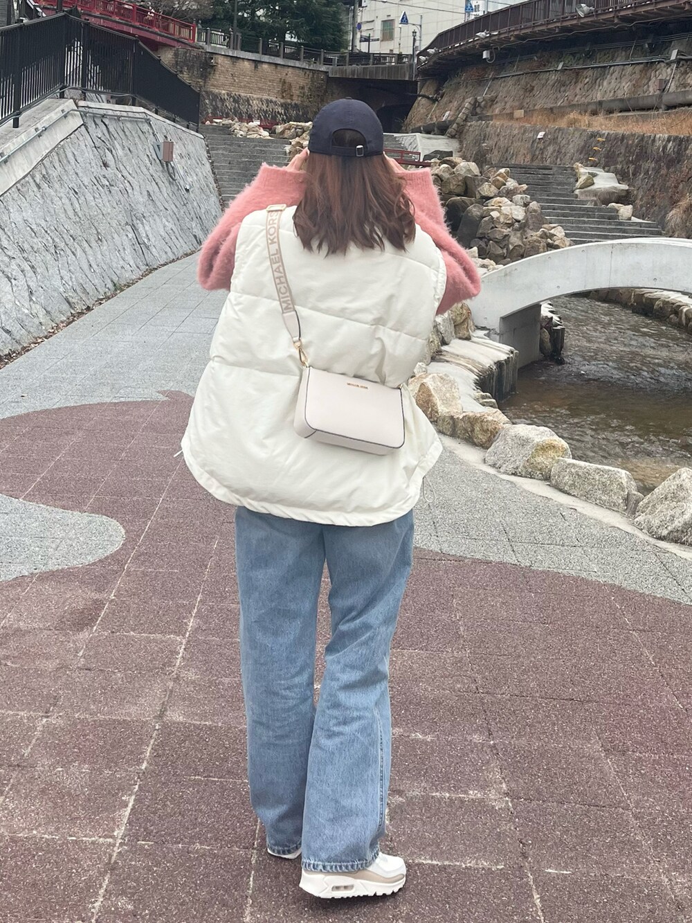 ピンク系のニット/セーター、ブルー系のデニムパンツ、ホワイト系のブルゾンを着用したレディースの春コーディネートの2枚目の写真