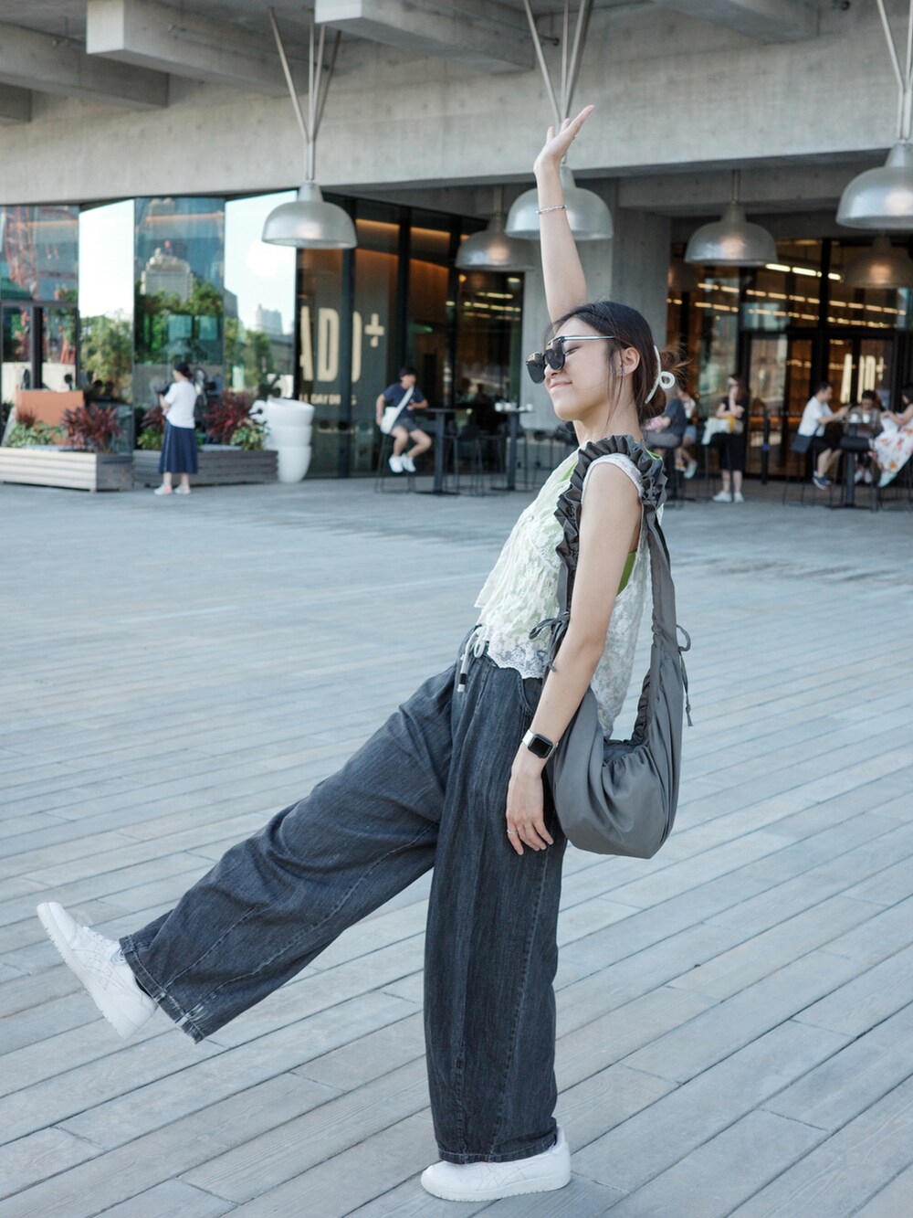 グリーン系のトップス、ホワイト系のスニーカー、ブラック系のサングラスを着用したレディースの夏コーディネートの2枚目の写真