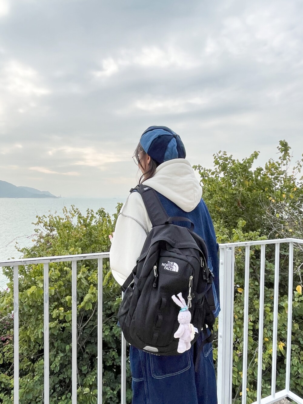 ブルー系のデニムジャケット、グレー系のスニーカー、ブラック系のバックパック/リュックを着用したレディースの冬コーディネートの4枚目の写真