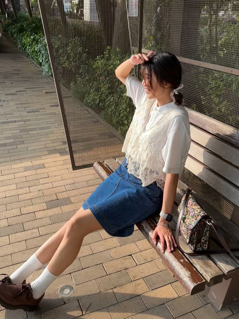 ホワイト系のポロシャツ、ブラウン系のシューズ、ブルー系のデニムスカートを着用したレディースの夏コーディネートの2枚目の写真