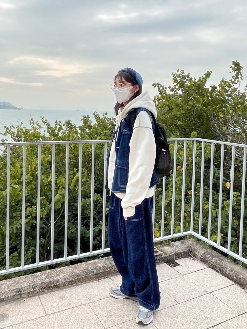 ブルー系のデニムジャケット、グレー系のスニーカー、ブラック系のバックパック/リュックを着用したレディースの冬コーディネートの2枚目の写真