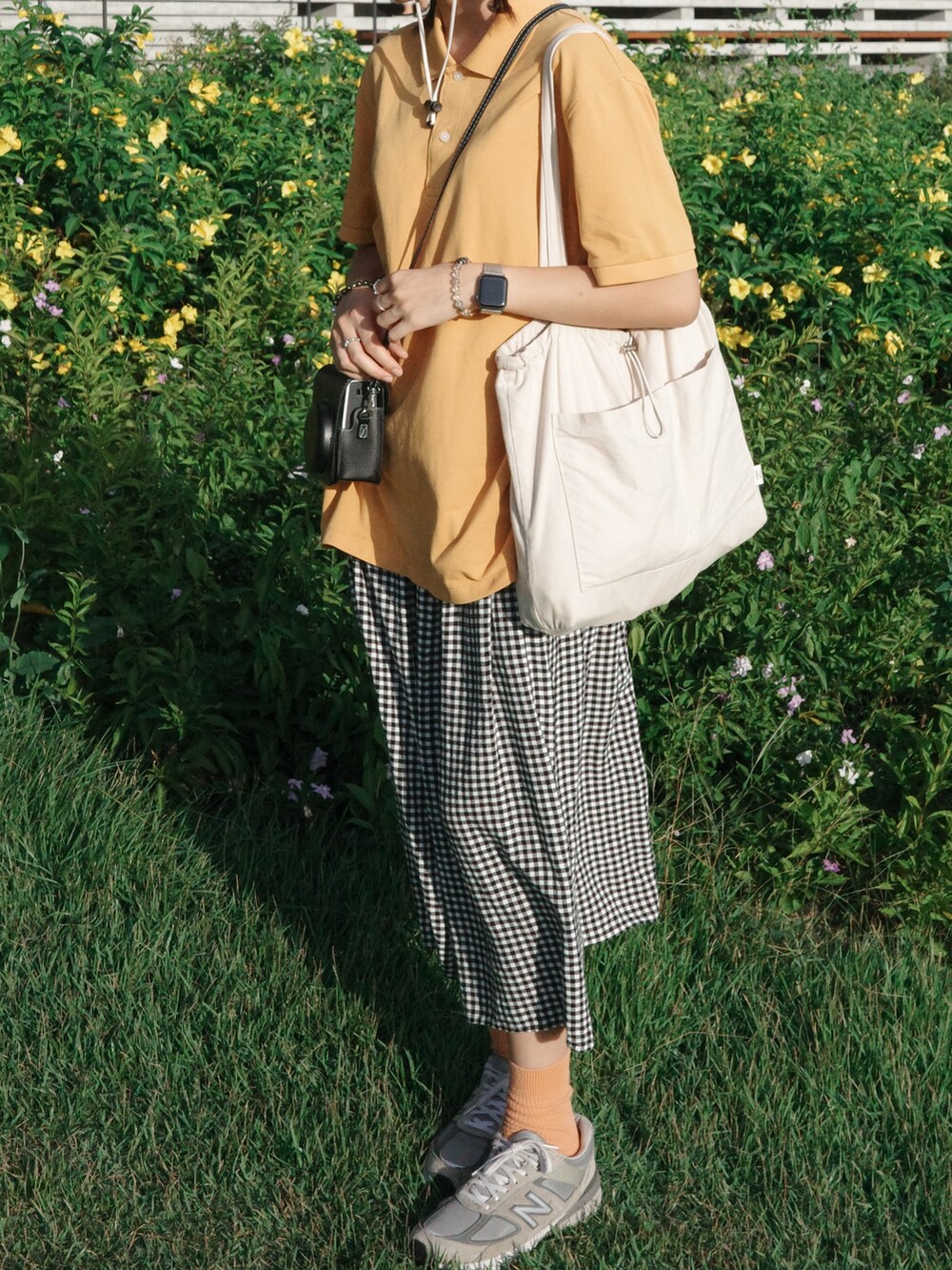 オレンジ系のポロシャツ、グレー系のスニーカー、オレンジ系のソックス/靴下を着用したレディースの夏コーディネートの2枚目の写真