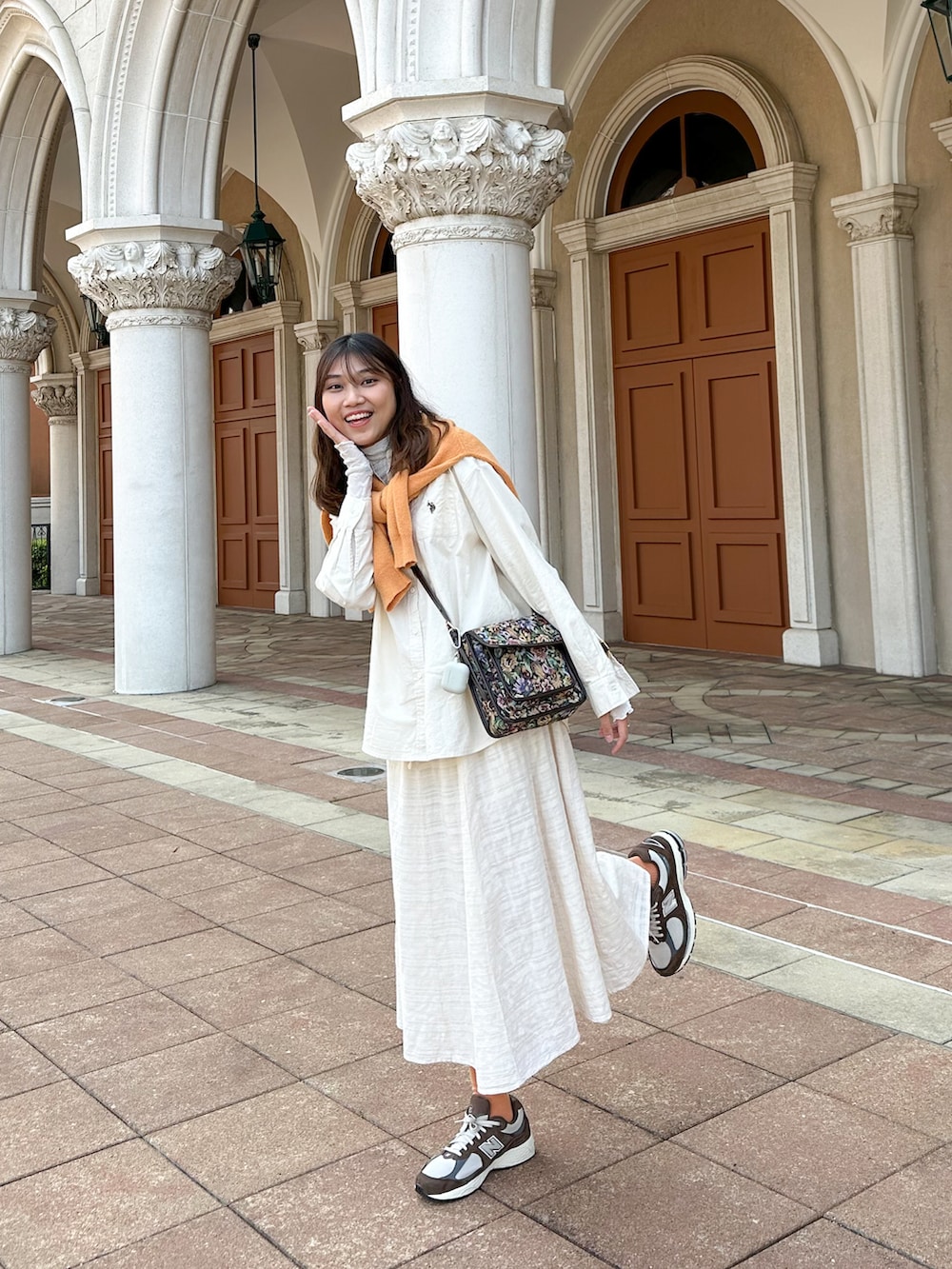 ホワイト系のシャツ/ブラウス、ブラウン系のスニーカー、オレンジ系のニット/セーターを着用したレディースの春コーディネートの2枚目の写真