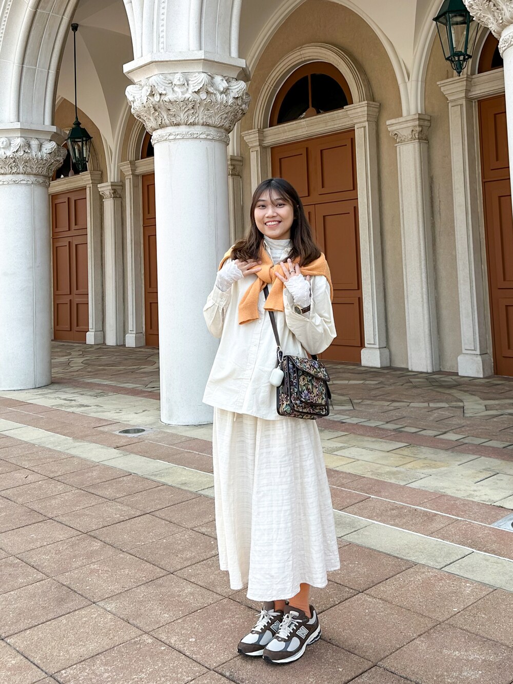 ホワイト系のシャツ/ブラウス、ブラウン系のスニーカー、オレンジ系のニット/セーターを着用したレディースの春コーディネートの3枚目の写真