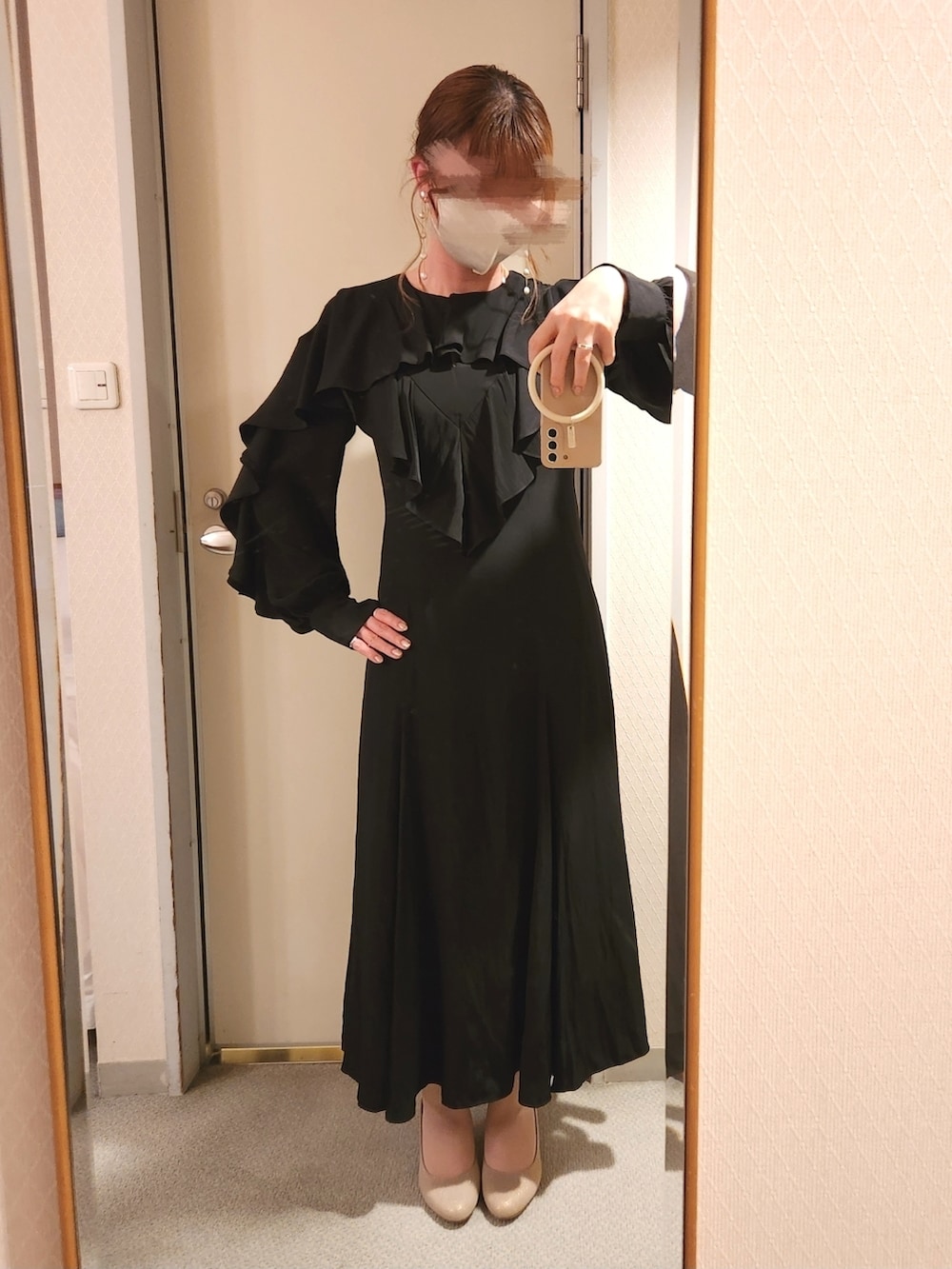 ブラック系のワンピース、ベージュ系のハンドバッグ、ゴールド系のパンプスを着用したレディースの夏コーディネートの2枚目の写真