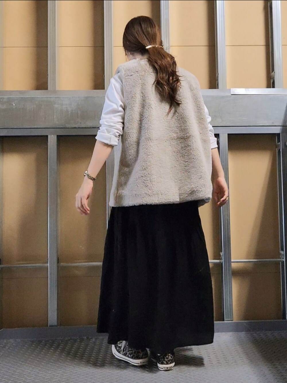 ベージュ系のベスト、ブラック系のスカート、その他のスニーカーを着用したレディースの秋コーディネートの3枚目の写真