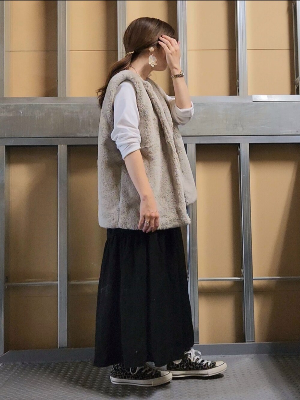 ベージュ系のベスト、ブラック系のスカート、その他のスニーカーを着用したレディースの秋コーディネートの2枚目の写真