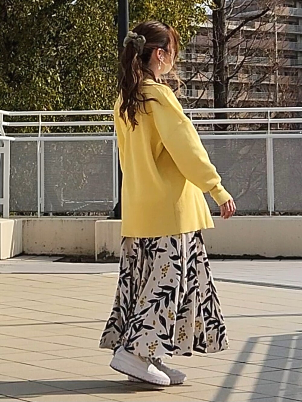 イエロー系のカーディガン/ボレロ、ホワイト系のスカート、ホワイト系のスニーカーを着用したレディースの春コーディネートの2枚目の写真