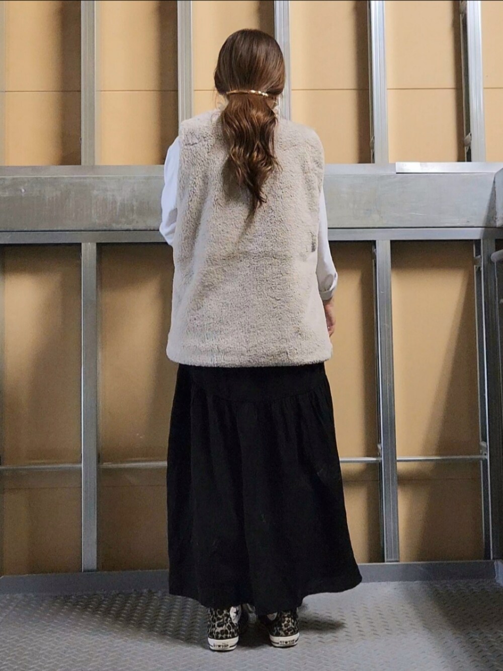 ベージュ系のベスト、ブラック系のスカート、その他のスニーカーを着用したレディースの秋コーディネートの4枚目の写真