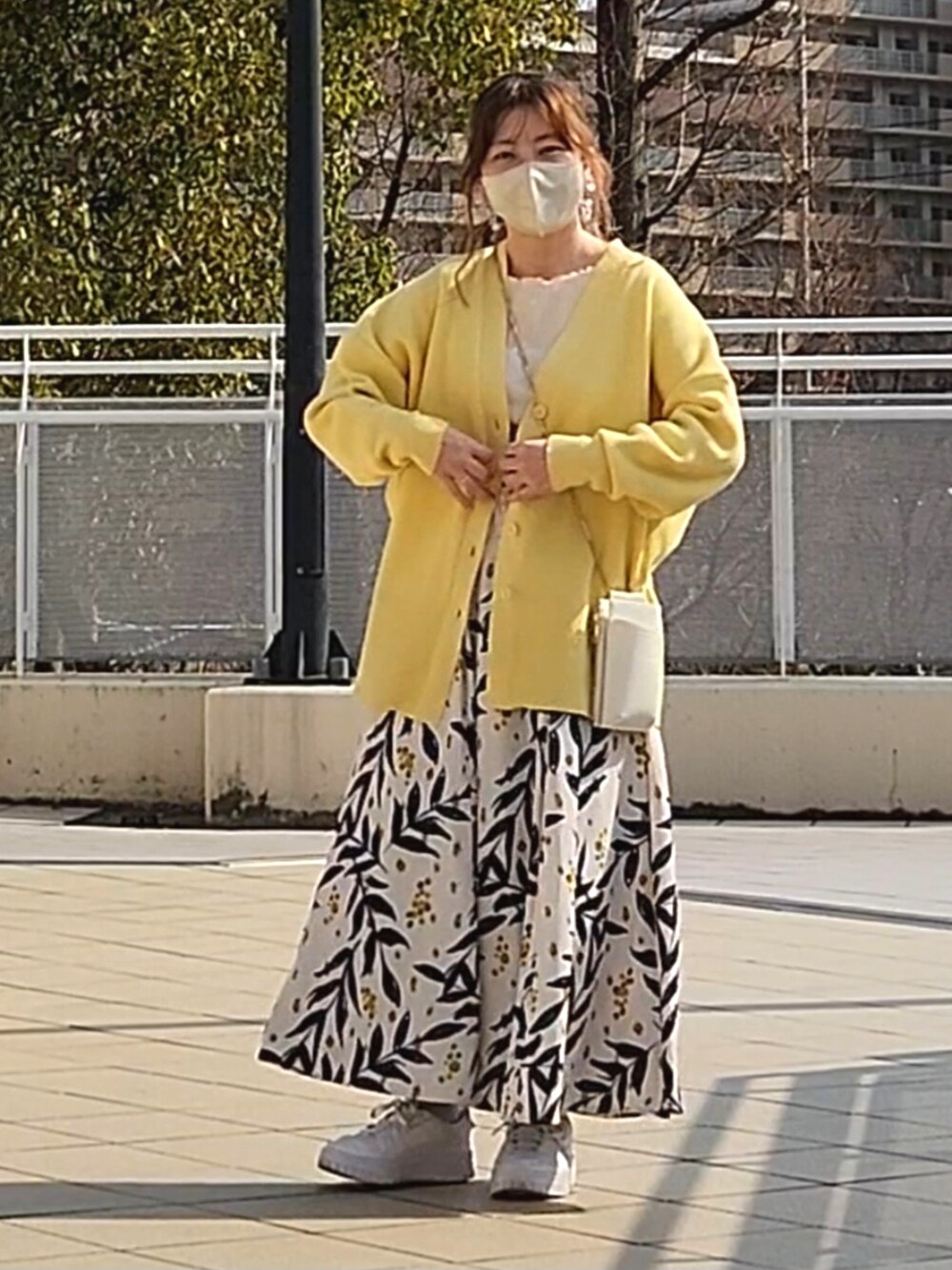 イエロー系のカーディガン/ボレロ、ホワイト系のスカート、ホワイト系のスニーカーを着用したレディースの春コーディネートの4枚目の写真