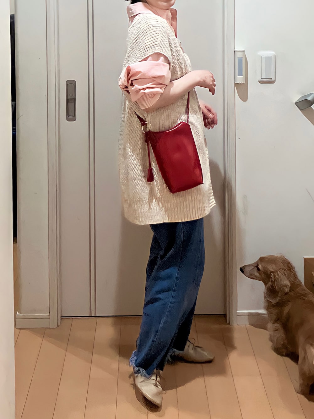 オレンジ系のシャツ/ブラウス、ベージュ系のベスト、ブルー系のデニムパンツを着用したレディースの春コーディネートの2枚目の写真