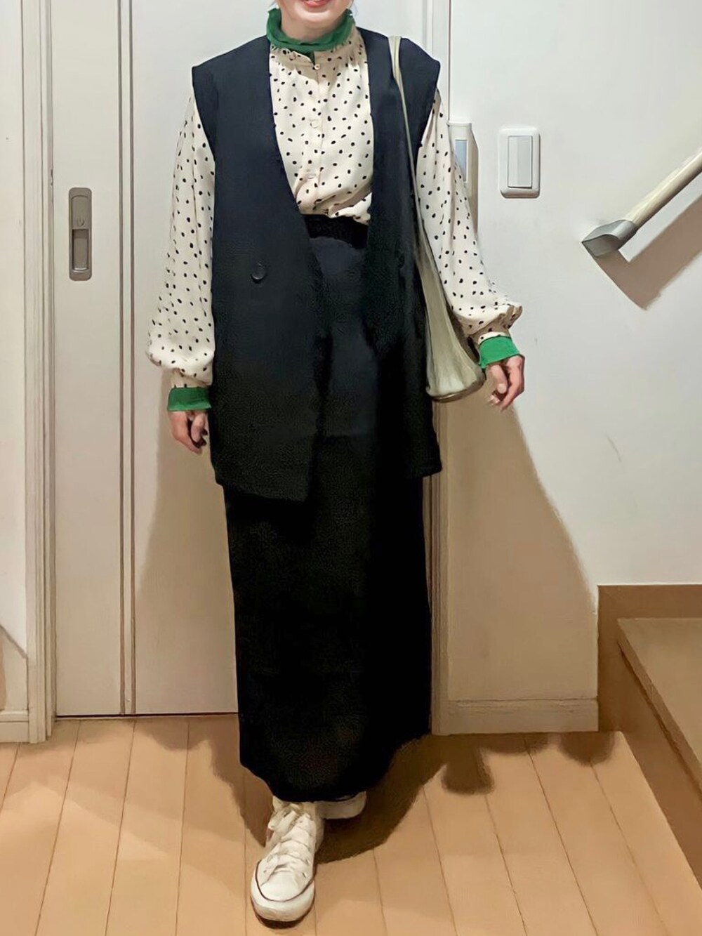 ブラック系のセットアップ、グリーン系のトップス、グリーン系のトートバッグを着用したレディースの春コーディネートの2枚目の写真