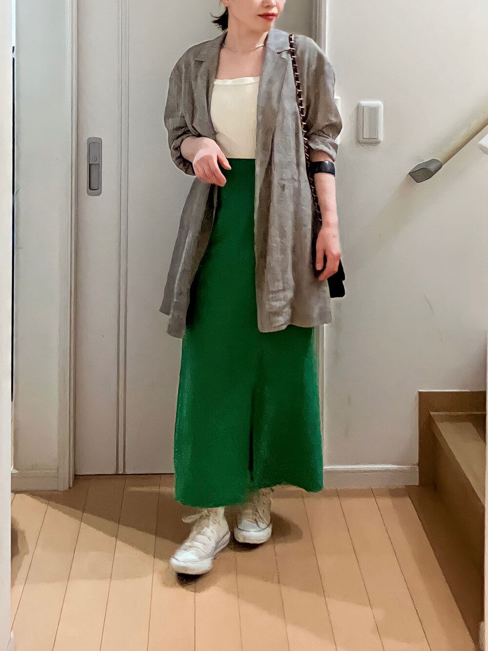 ブラウン系のテーラードジャケット、ホワイト系のタンクトップ、グリーン系のスカートを着用したレディースの春コーディネートの2枚目の写真