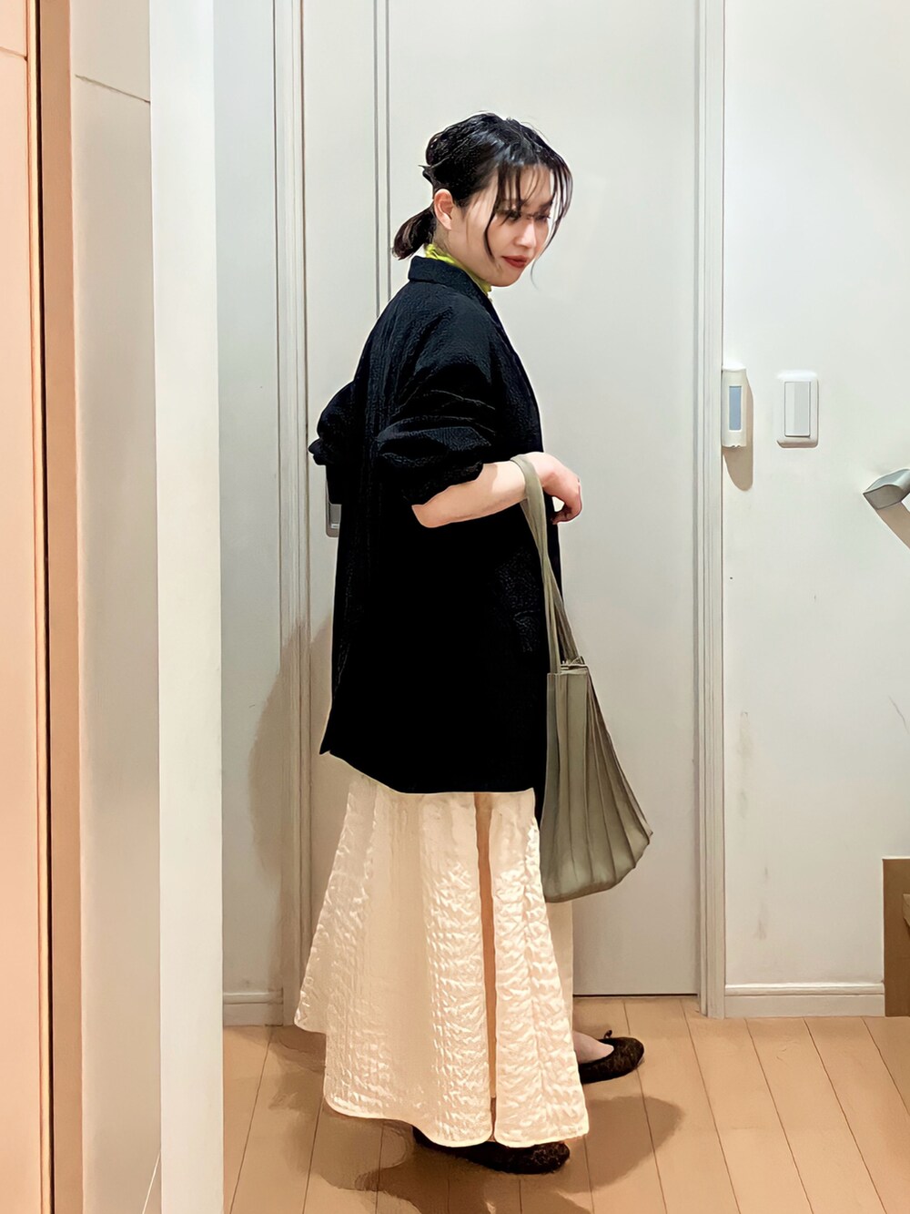 ブラック系のテーラードジャケット、グリーン系のTシャツ/カットソー、ホワイト系のスカートを着用したレディースの春コーディネートの2枚目の写真