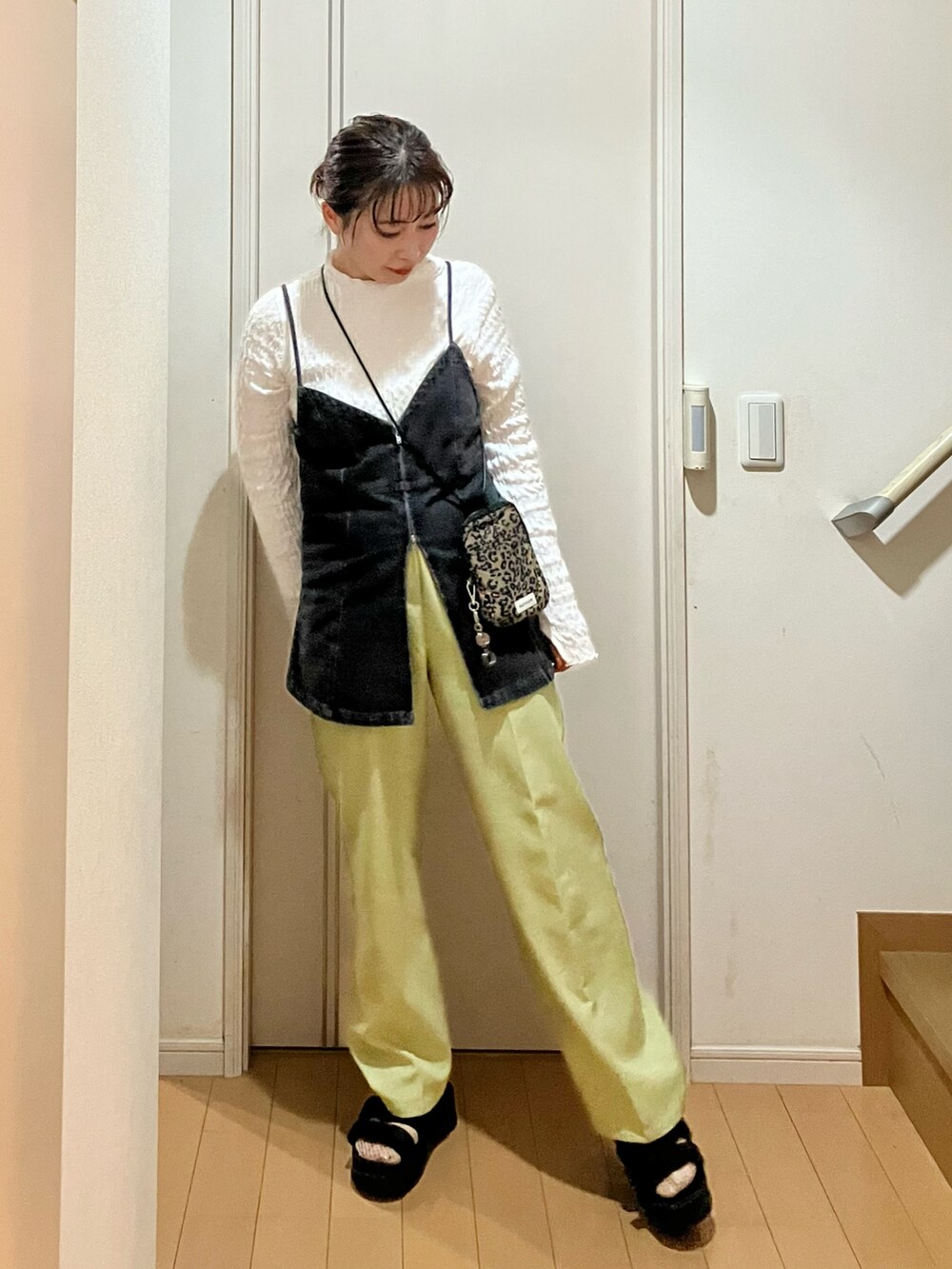 ブラック系のベスト、グリーン系のスラックス、ブラウン系のショルダーバッグを着用したレディースの秋コーディネートの2枚目の写真