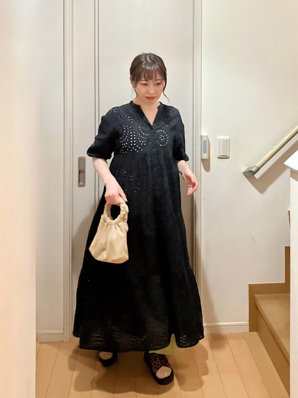 ブラック系のワンピース、ベージュ系のショルダーバッグ、グリーン系のスラックスを着用したレディースの夏コーディネートの2枚目の写真