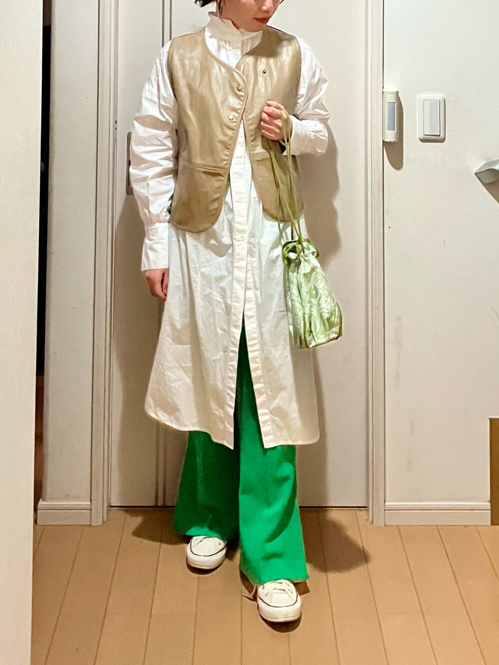 ホワイト系のシャツ/ブラウス、ベージュ系のベスト、グリーン系のハンドバッグを着用したレディースの春コーディネートの2枚目の写真