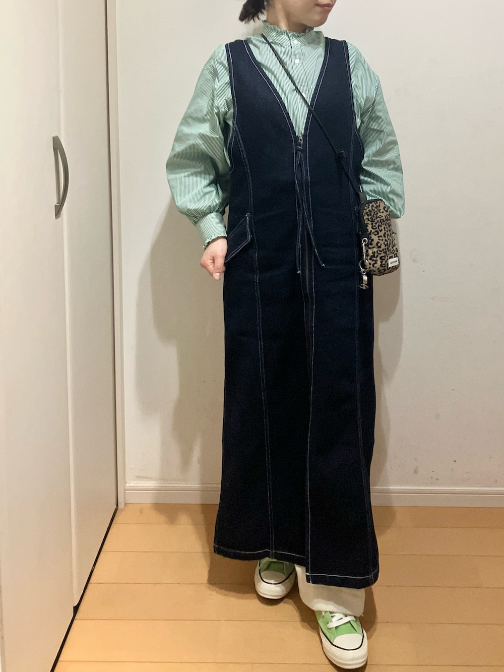 グリーン系のシャツ/ブラウス、ブルー系のジャンパースカート、グリーン系のスニーカーを着用したレディースの春コーディネートの2枚目の写真