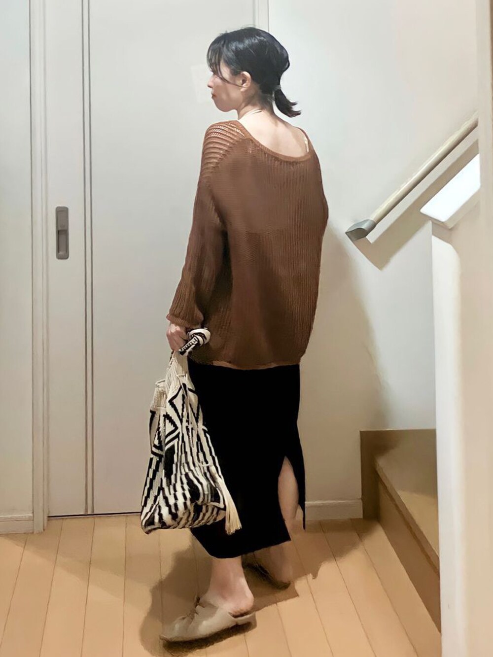 ブラウン系のニット/セーター、ホワイト系のショルダーバッグ、ブラック系のスカートを着用したレディースの春コーディネートの2枚目の写真