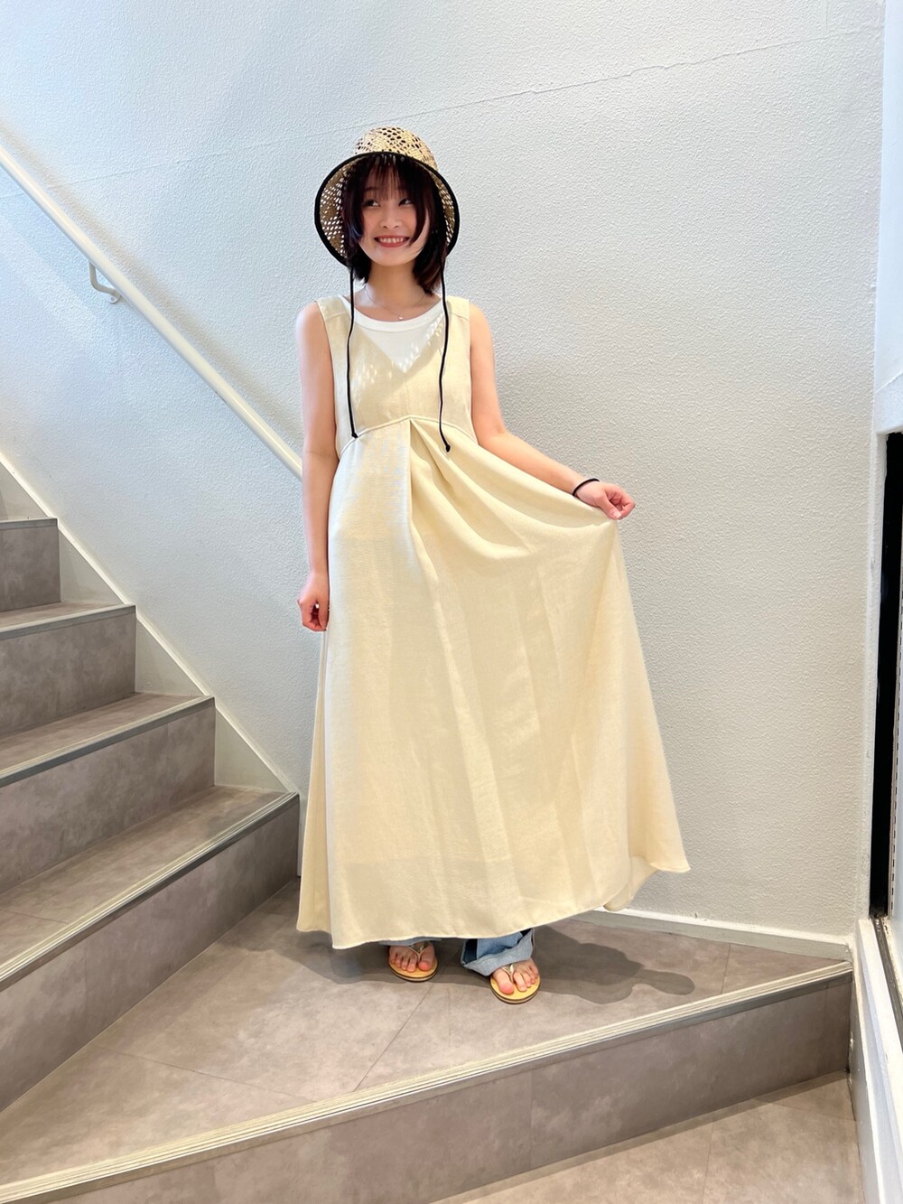 ベージュ系のワンピース、ブルー系のデニムパンツ、ベージュ系のサンダルを着用したレディースの夏コーディネートの2枚目の写真