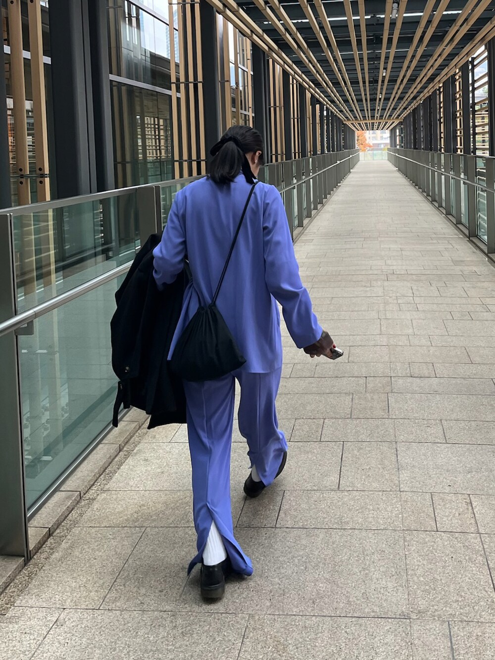 パープル系のスラックス、パープル系のシャツ/ブラウス、ブラック系のローファーを着用したレディースの冬コーディネートの2枚目の写真