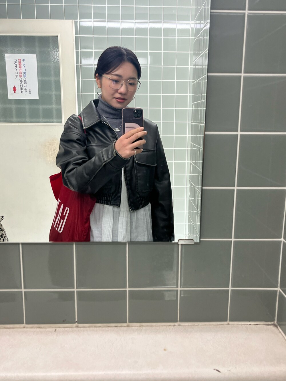 ブラウン系のライダースジャケット、ホワイト系のワンピース/ドレス、レッド系のトートバッグを着用したレディースの冬コーディネートの4枚目の写真