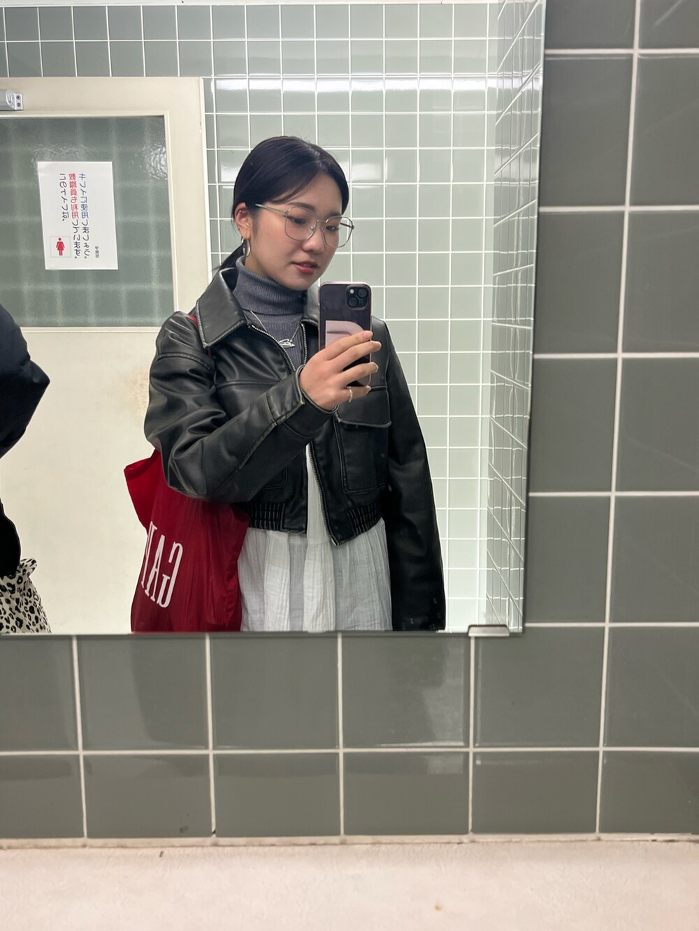 ブラウン系のライダースジャケット、ホワイト系のワンピース/ドレス、レッド系のトートバッグを着用したレディースの冬コーディネートの3枚目の写真