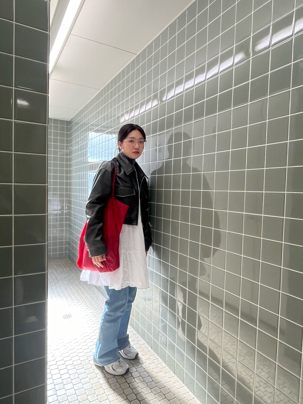 ブラウン系のライダースジャケット、ホワイト系のワンピース/ドレス、レッド系のトートバッグを着用したレディースの冬コーディネートの2枚目の写真