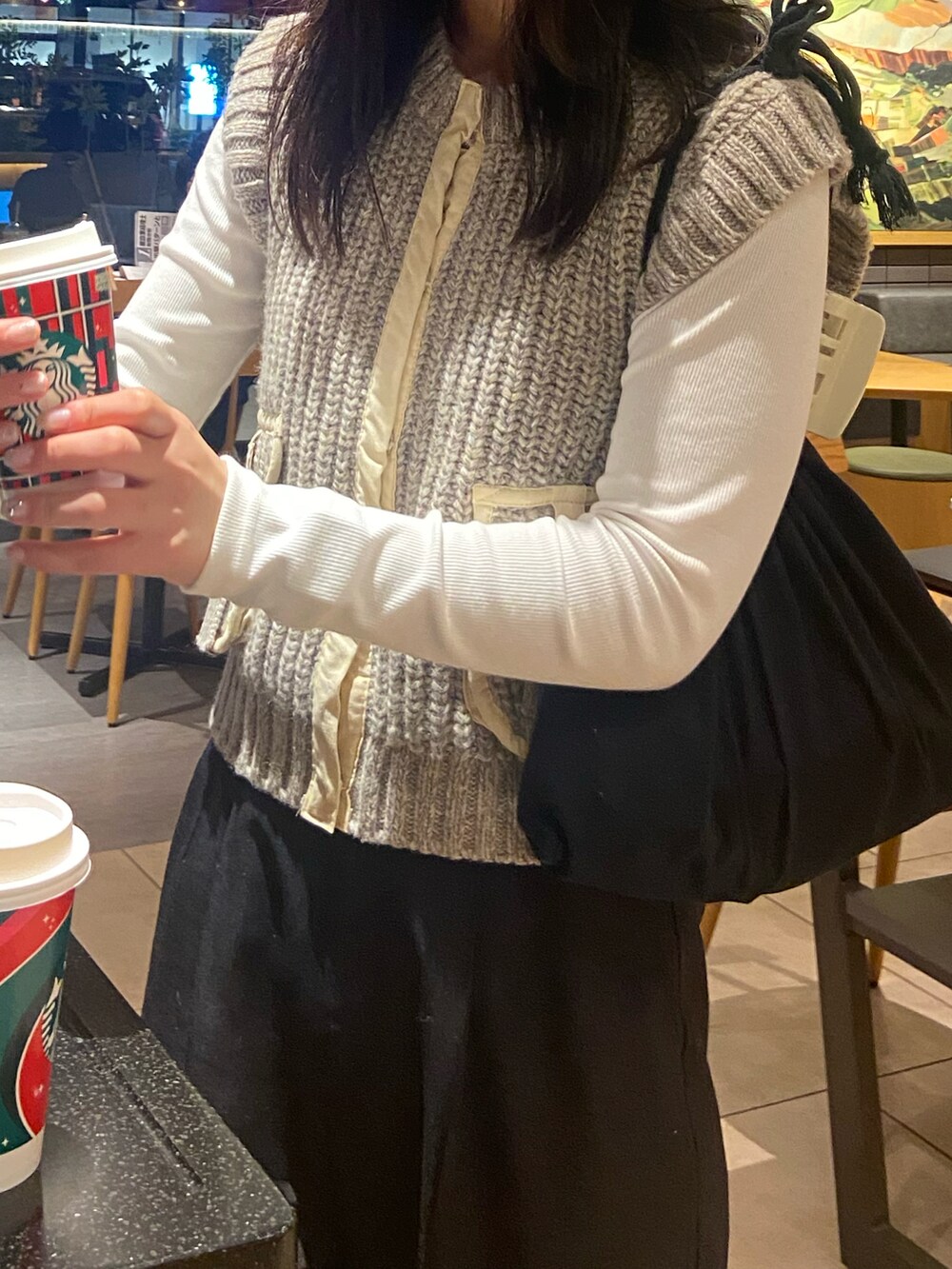 ブラック系のスラックス、ベージュ系のモカシン/デッキシューズ、ベージュ系のベストを着用したレディースの冬コーディネートの2枚目の写真